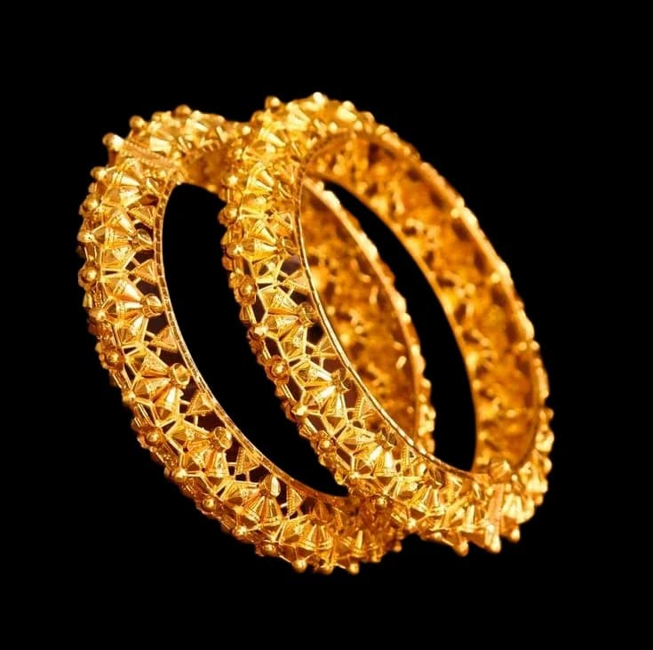 A pair of ornate gold bangles with intricate filigree detailing